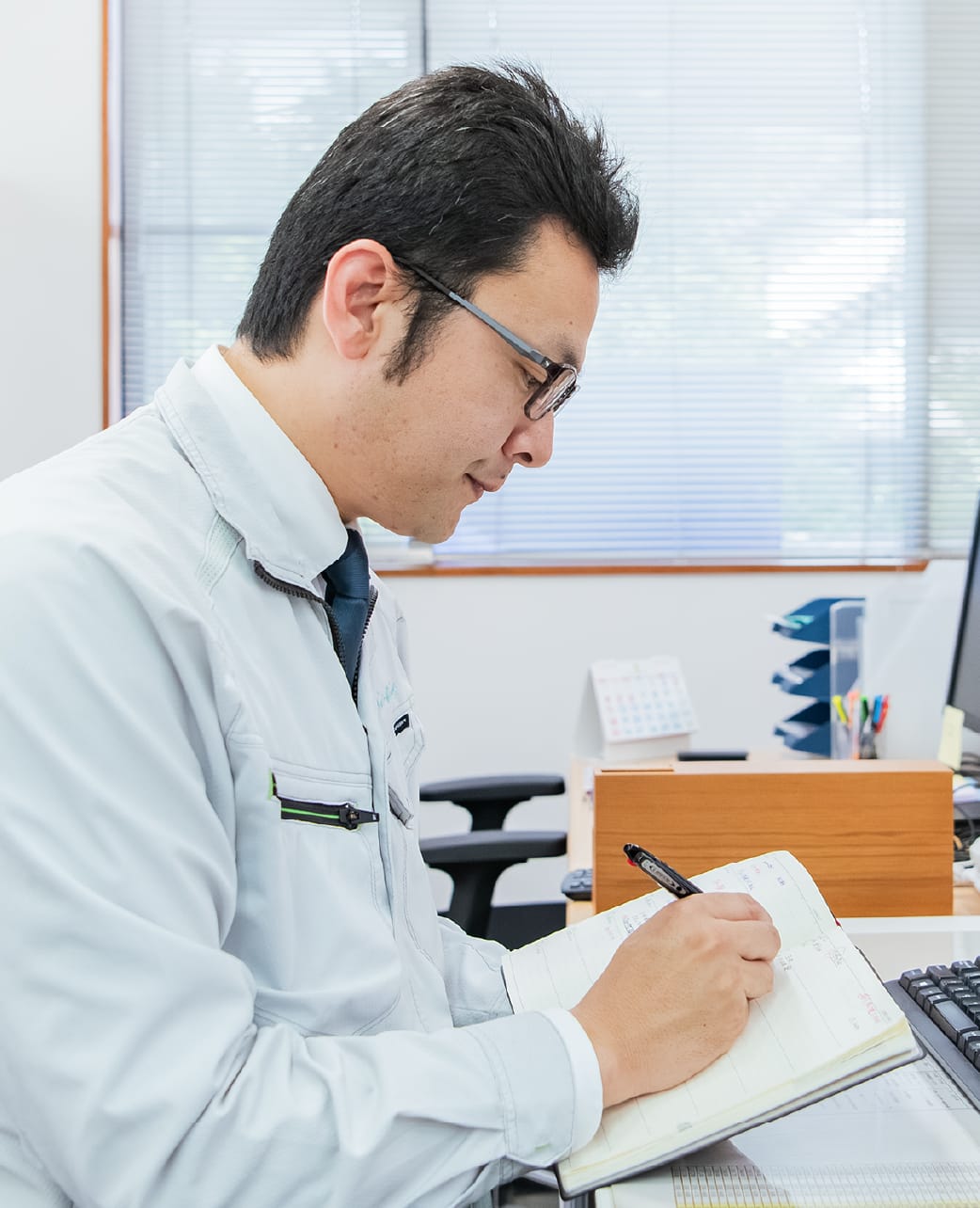 ノートに記入する作業服姿の男性